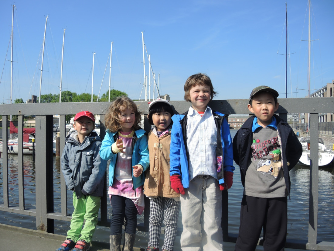 Fünf Kinder stehen an einem Zaun am Hafen