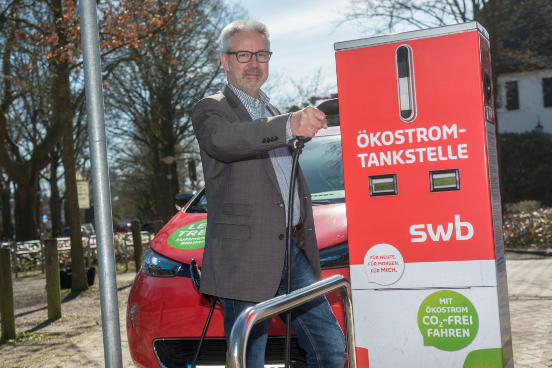 Ein Mann im Anzug lädt sein Elektroauto an einer SWB-Ladesäule