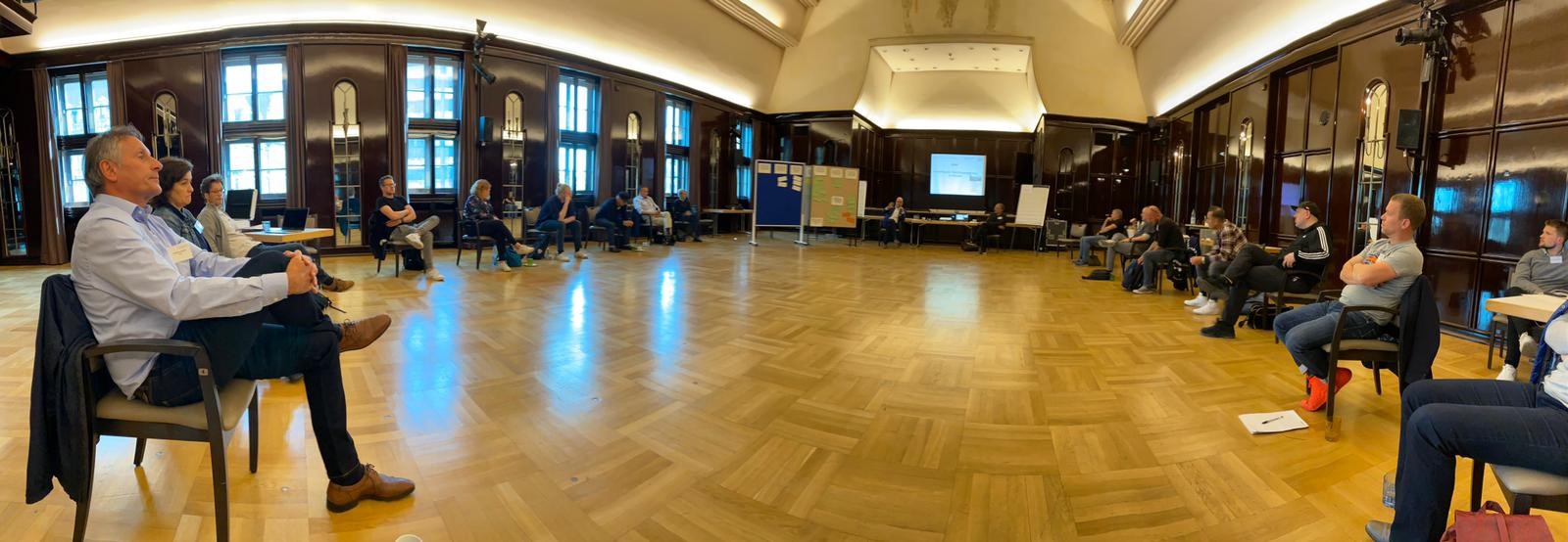 Menschen sitzen in einem großen Saal im Kreis