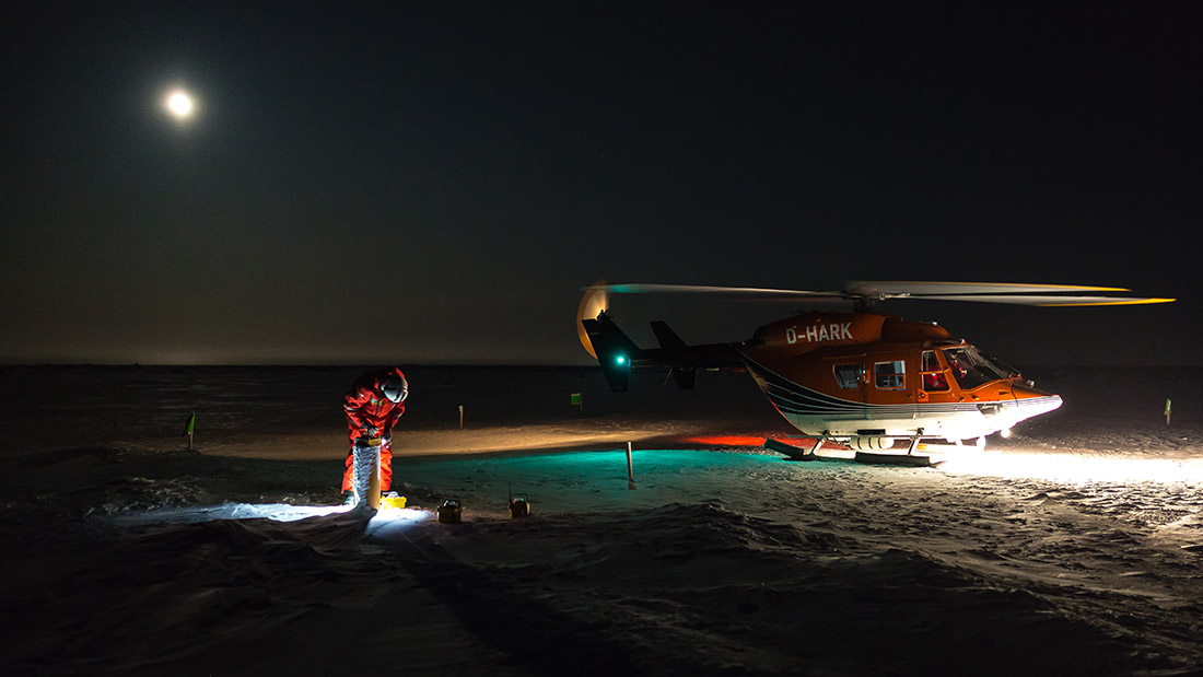 Ein Helikopter und ein Forscher im Dunklen bei Schnee