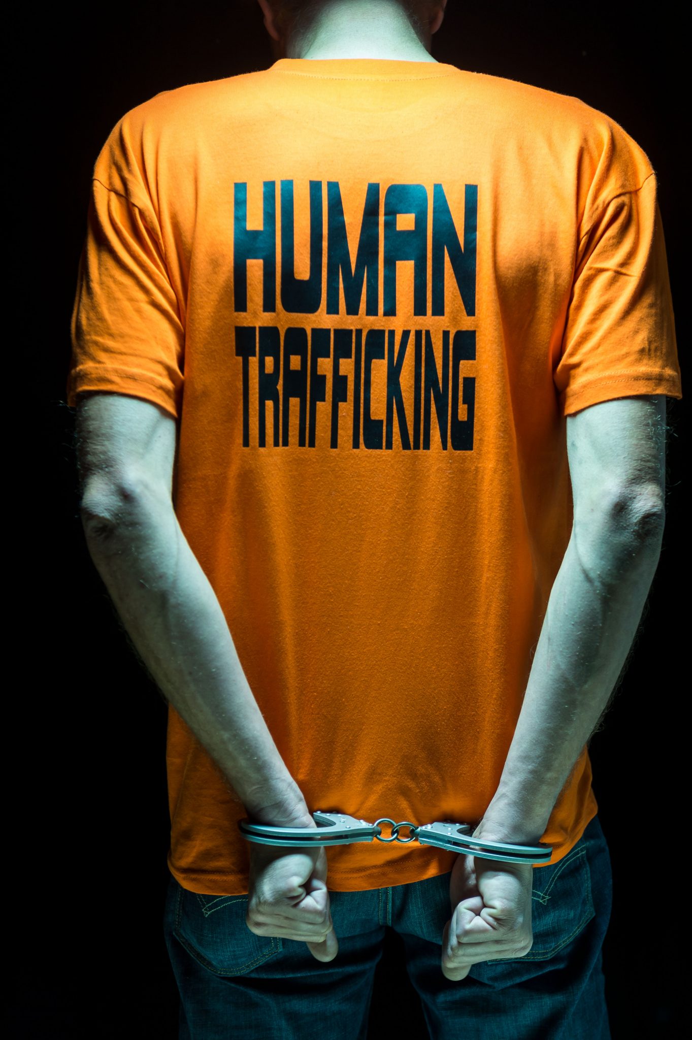 Mann von hinten in Handschellen, der ein T-Shit mit der Aufschrift Human trafficking" trägt