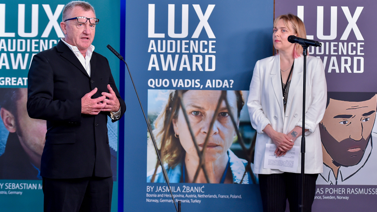 Zwei Personen unterhalten sich vor einer Plakatwand des LUX Audience Awards