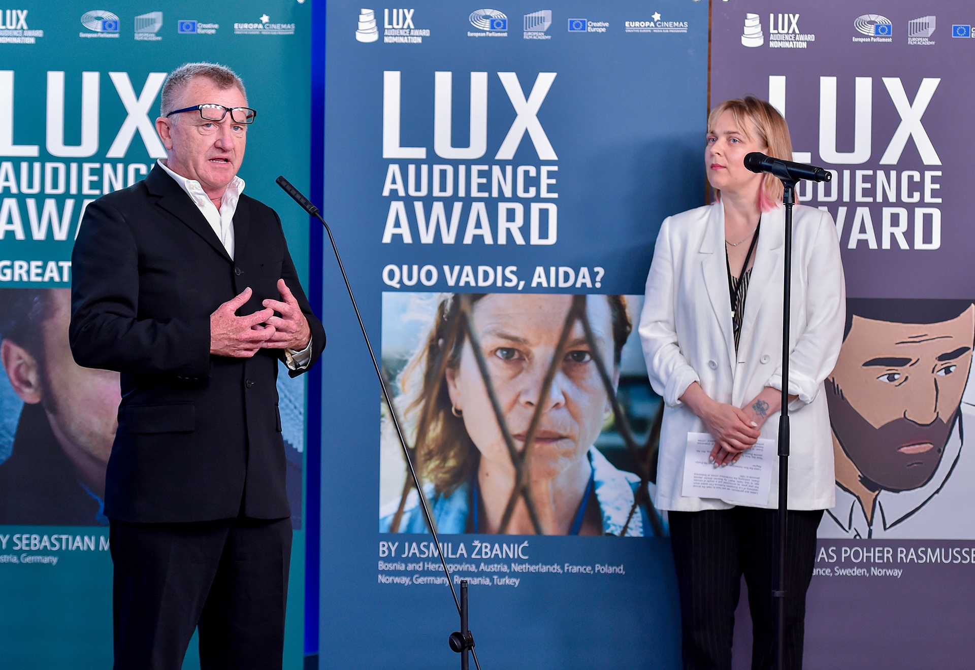 Zwei Personen unterhalten sich vor einer Plakatwand des LUX Audience Awards