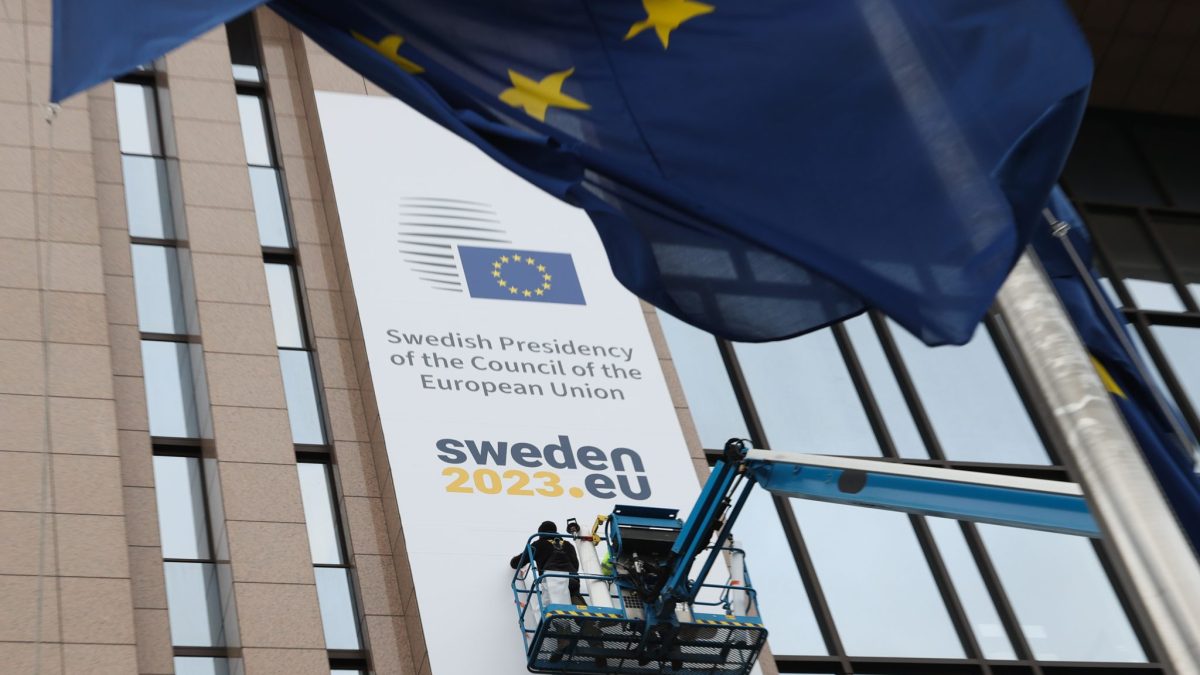 Ein Plakat der "Swedisch Presidency of the Coucil of the European Union" wird an einem Gebäude befestigt