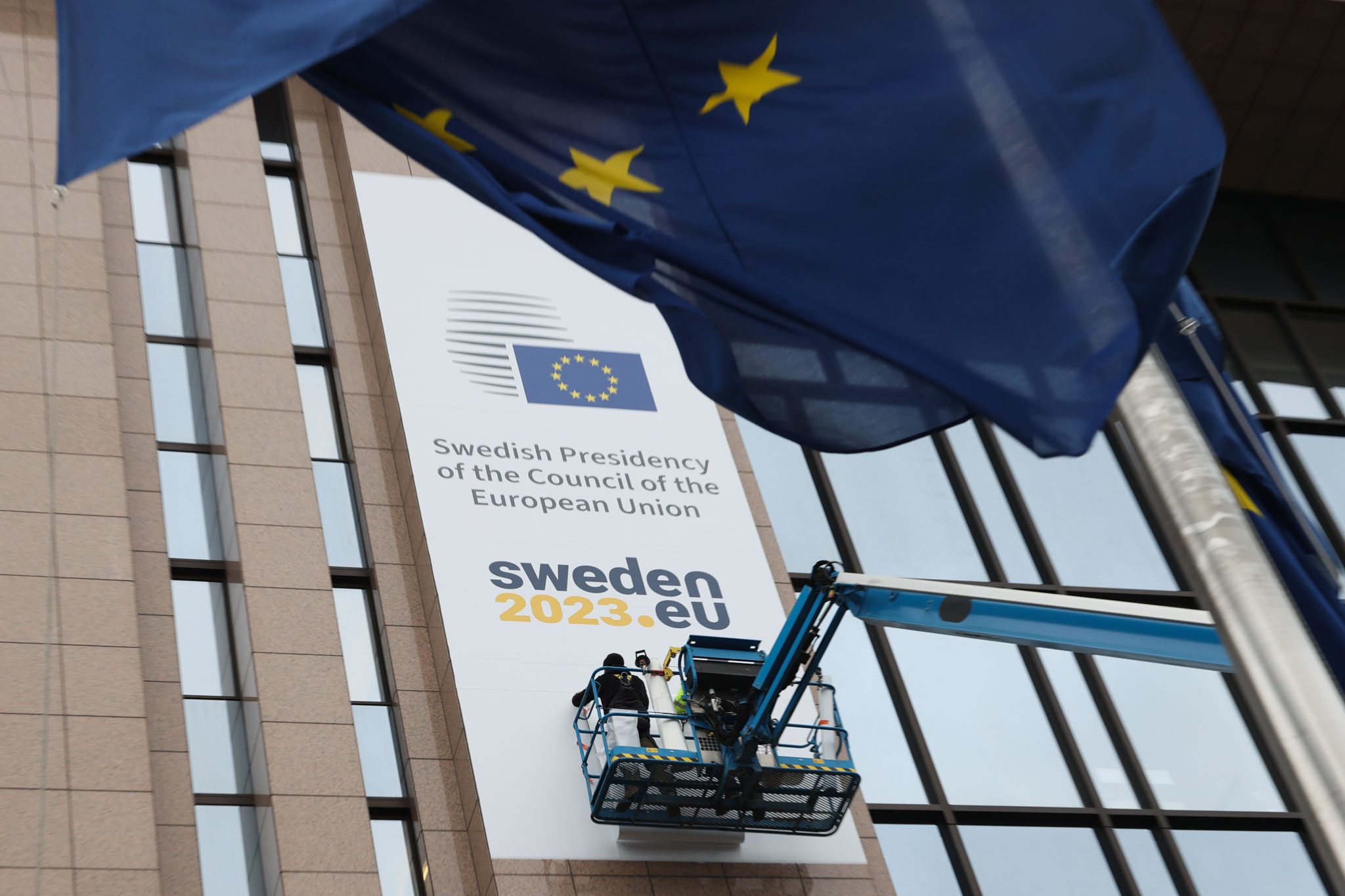 Ein Plakat der "Swedisch Presidency of the Coucil of the European Union" wird an einem Gebäude befestigt