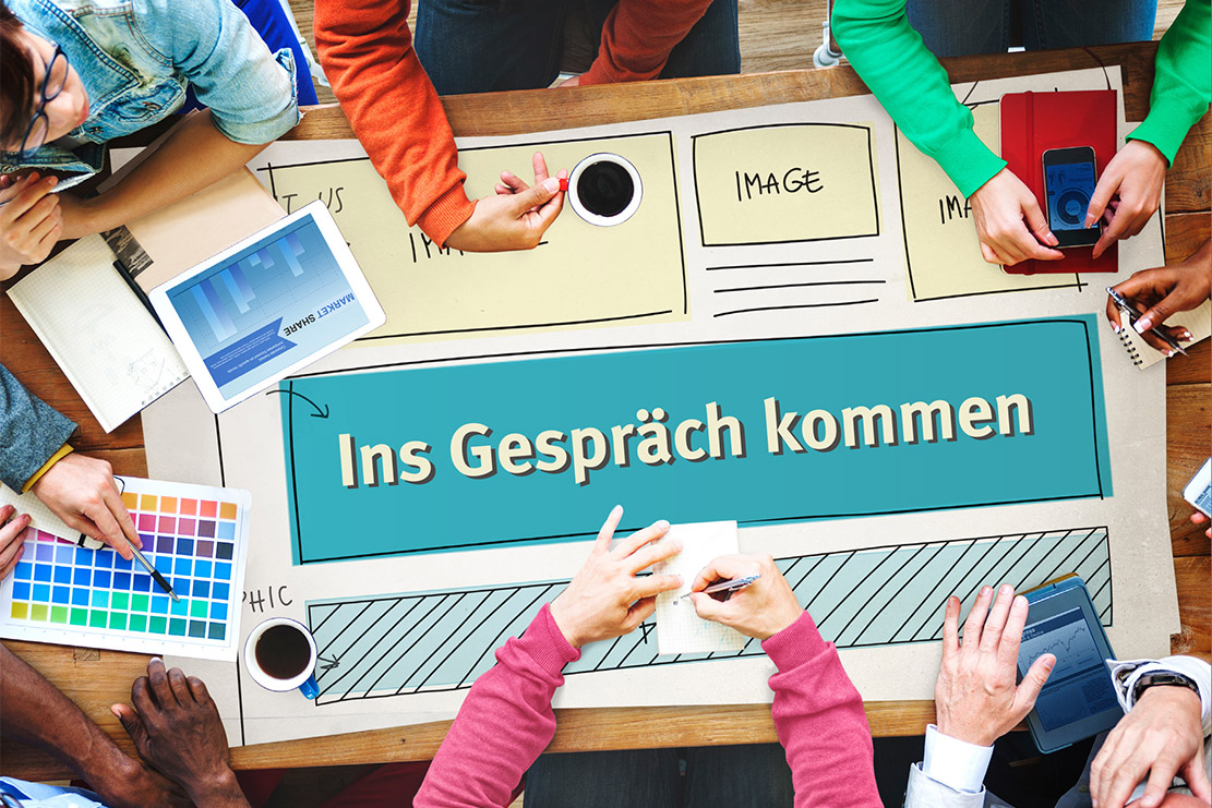 Mehrere Kinder arbeiten an einem Plakat auf dem Plakat steht "Ins Gespräch kommen"