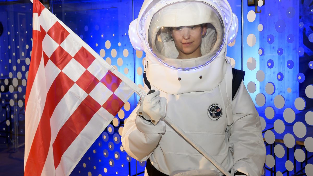 Ein Kind im Astronautenanzug hält eine Flagge