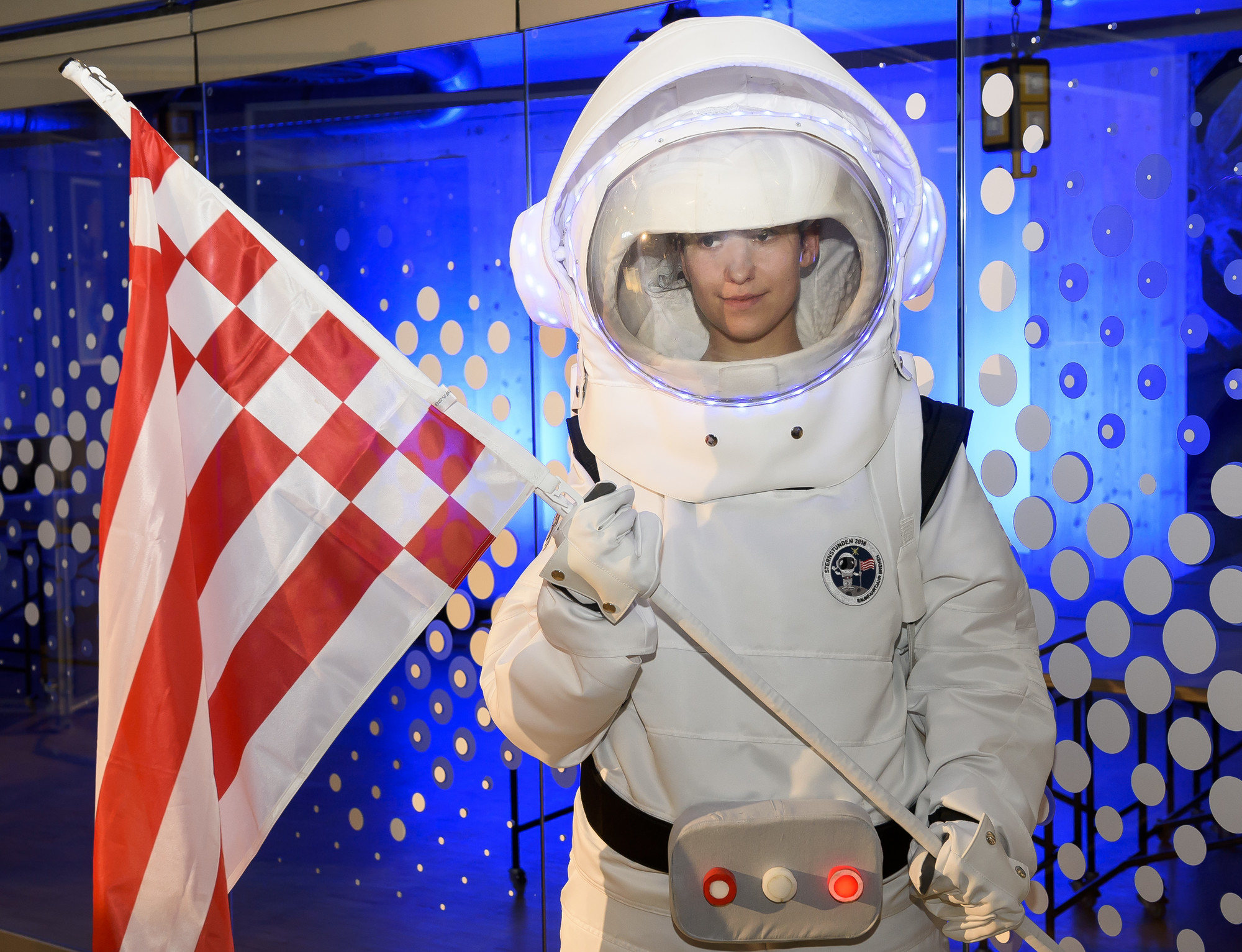 Ein Kind im Astronautenanzug hält eine Flagge